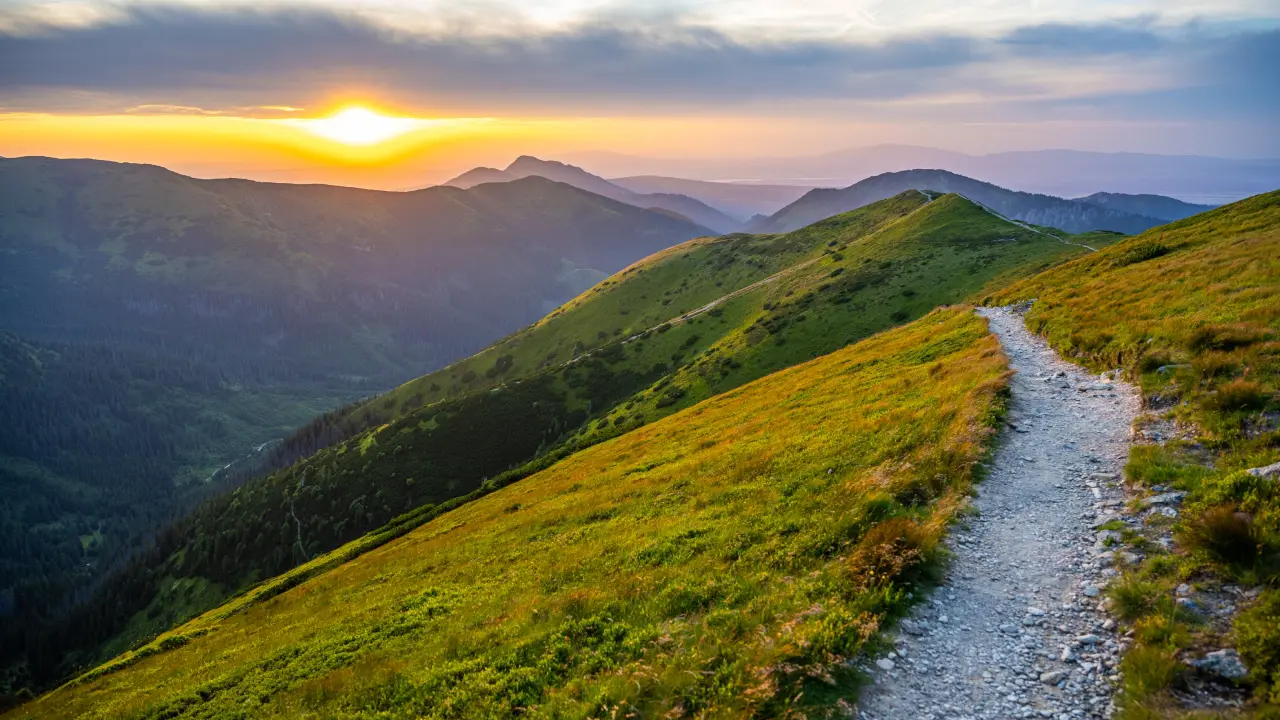 Mountain trail at sunset with vibrant sky.