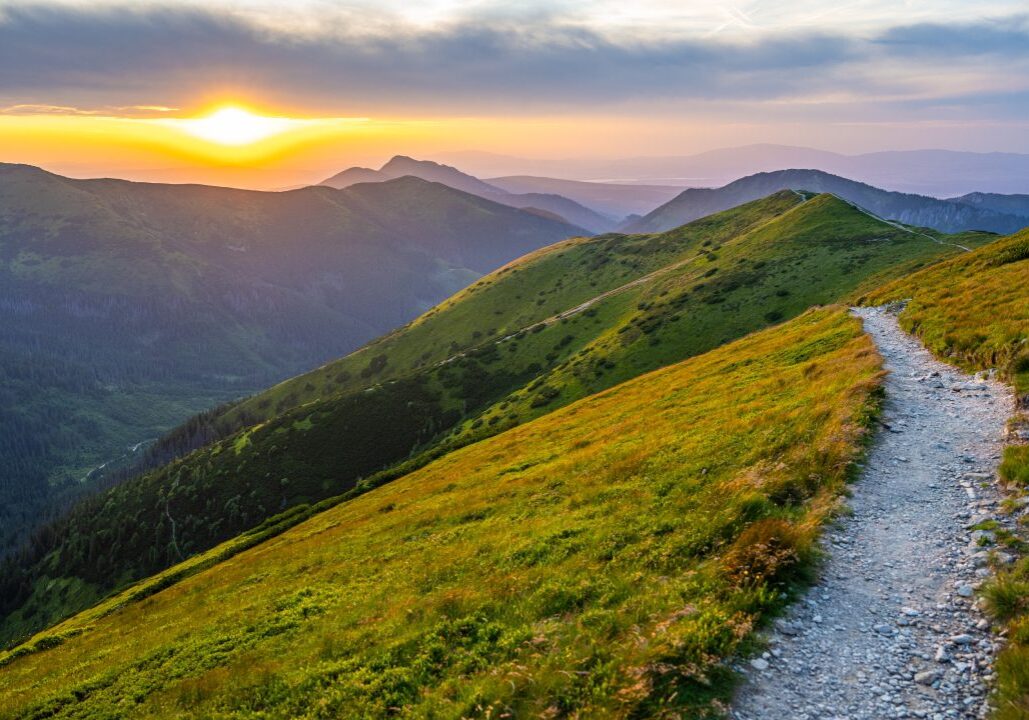 Mountain trail at sunset with vibrant sky.